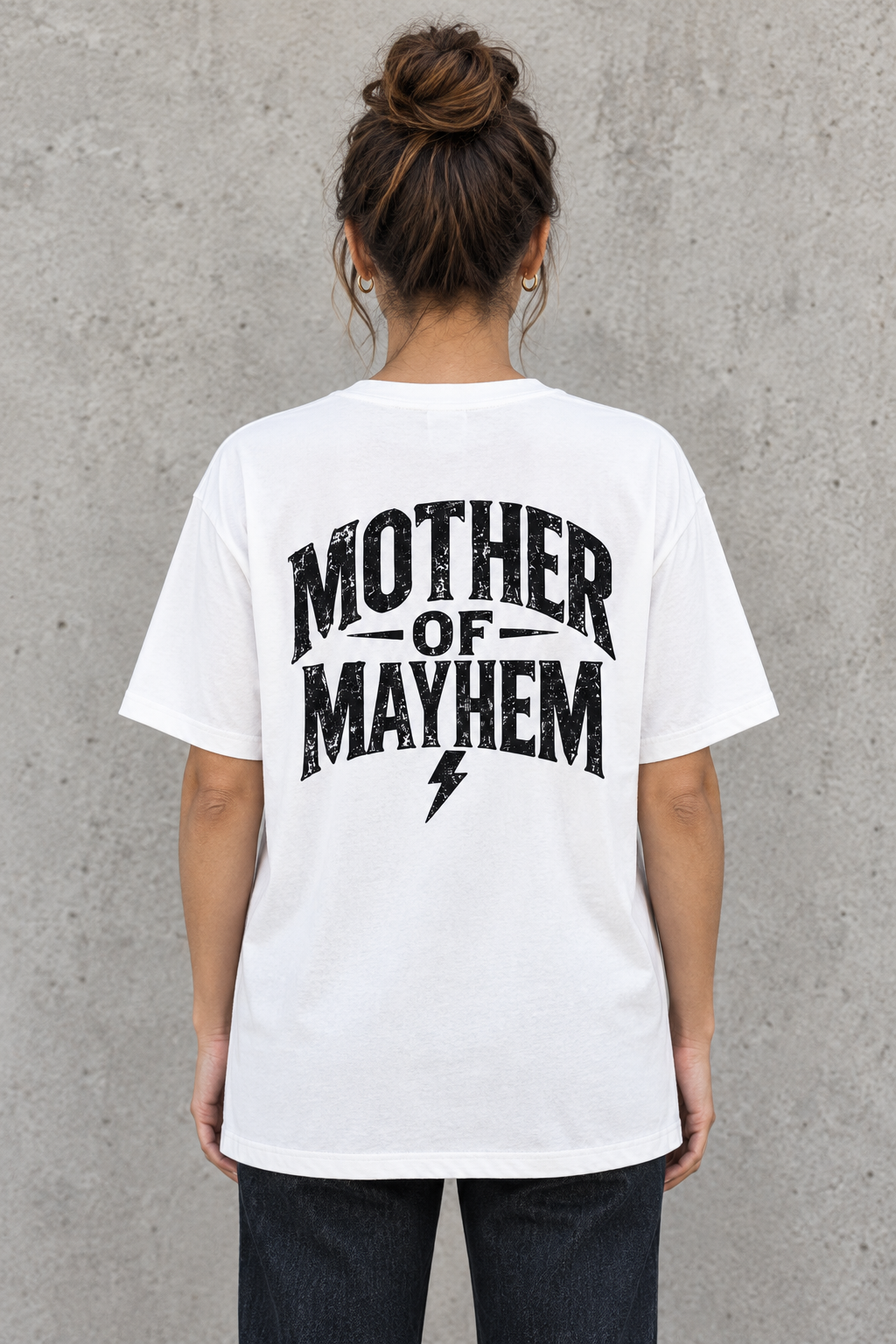 AI-generated mockup of a woman wearing the white loose-fit tee, showing the Mother of Mayhem back graphic and lightning bolt.