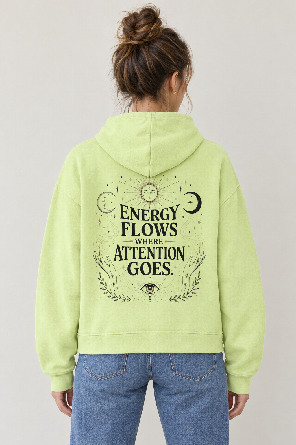 AI-generated back-view mockup of a woman wearing the Light Green Energy Flows Where Attention Goes graphic hoodie.