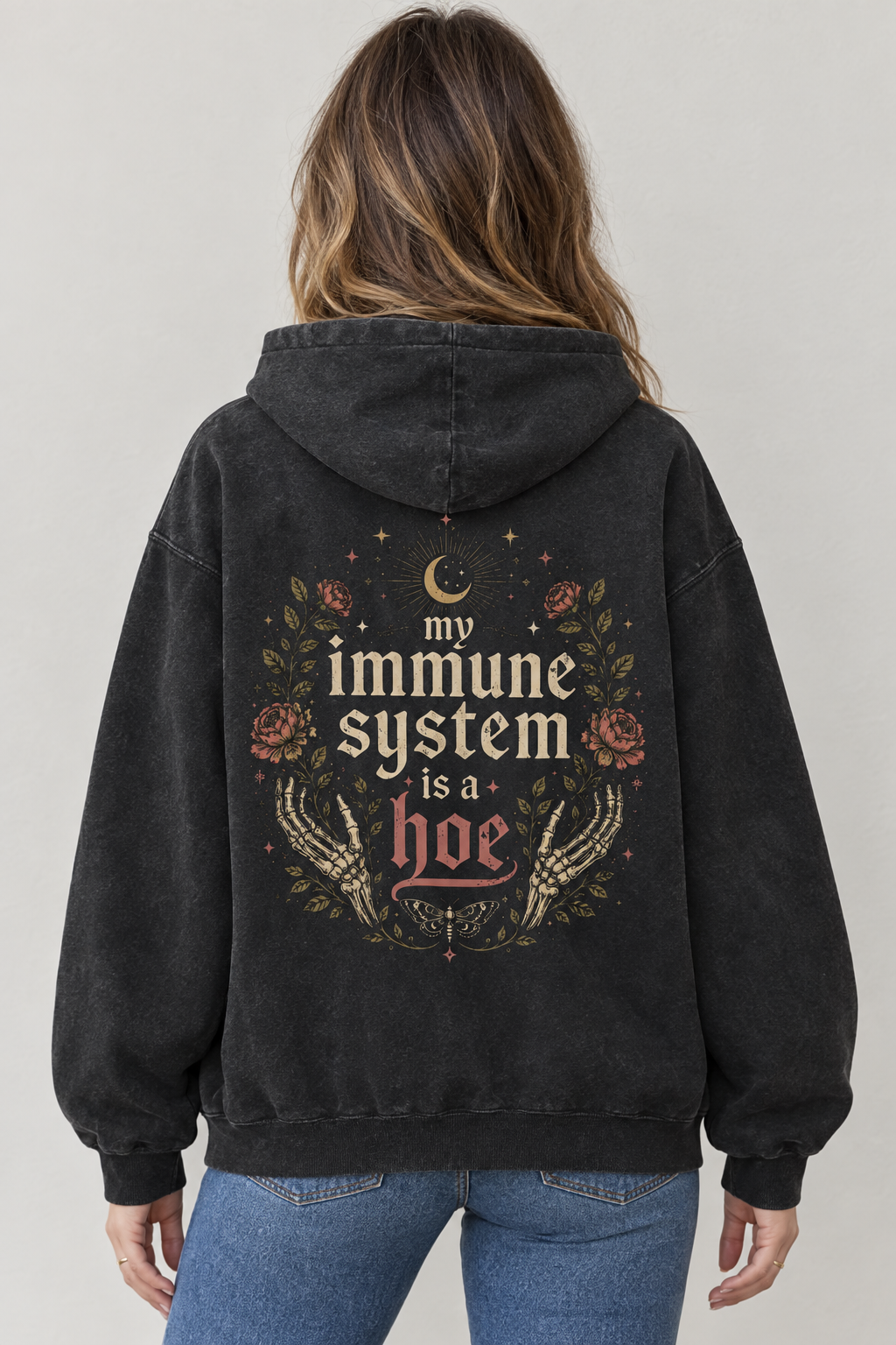 AI-generated back-view mockup of a woman wearing the washed black My Immune System Is a Hoe hoodie with roses, skeletal hands and celestial artwork.