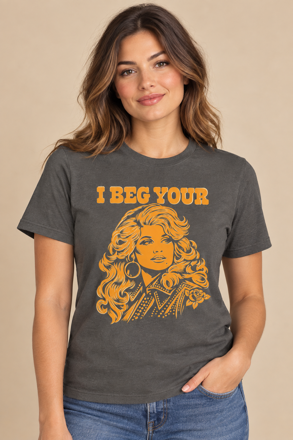 Woman wearing a charcoal gray I Beg Your graphic T-shirt with golden-orange lettering and an illustrated portrait.