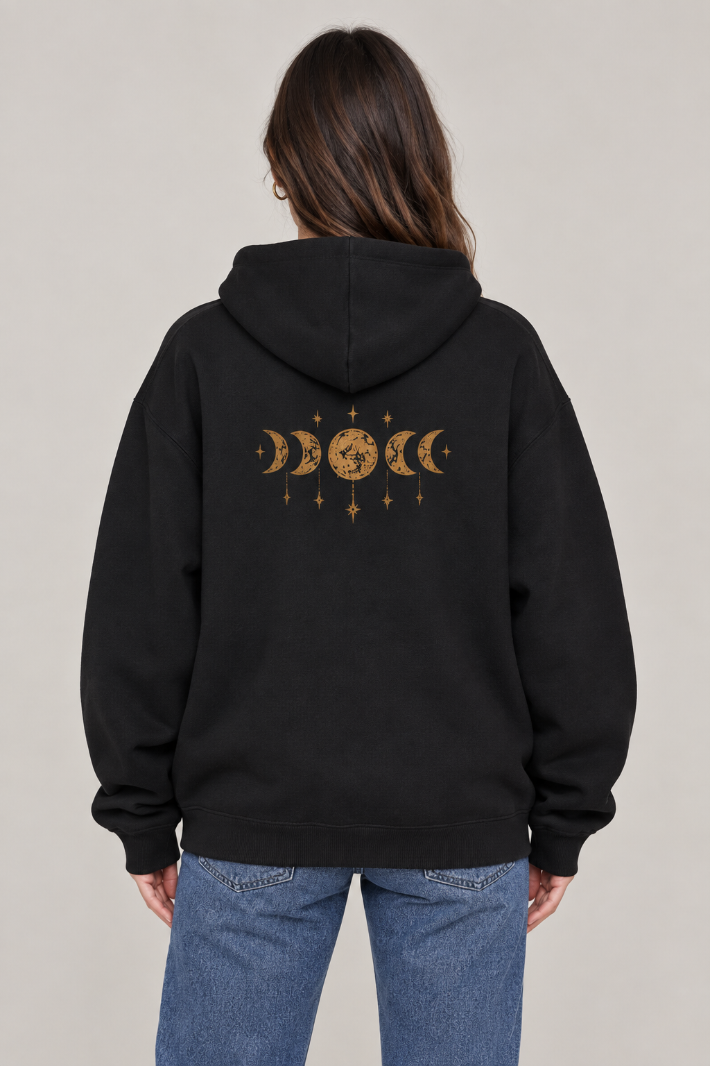 Back view of a woman wearing a black oversized hoodie with gold moon phases and hanging stars.