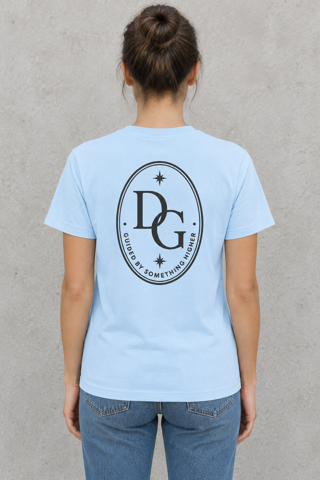AI-generated back-view mockup of a woman wearing the Sky Blue Divine Grit DG crest tee with Guided by Something Higher artwork.