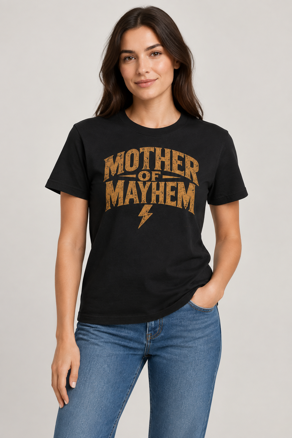 Woman wearing a black Mother of Mayhem cotton graphic tee with distressed gold-toned lettering and a lightning bolt.